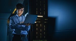 IT professional working on a laptop in a server room