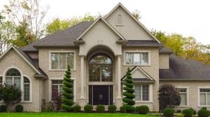 Large, multi-story brick home with polished landscaping